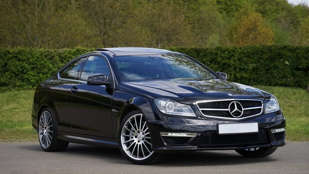 Import Car from Korea to UAE Luxurious black Mercedes Benz coupe parked on a scenic outdoor setting with lush greenery.
